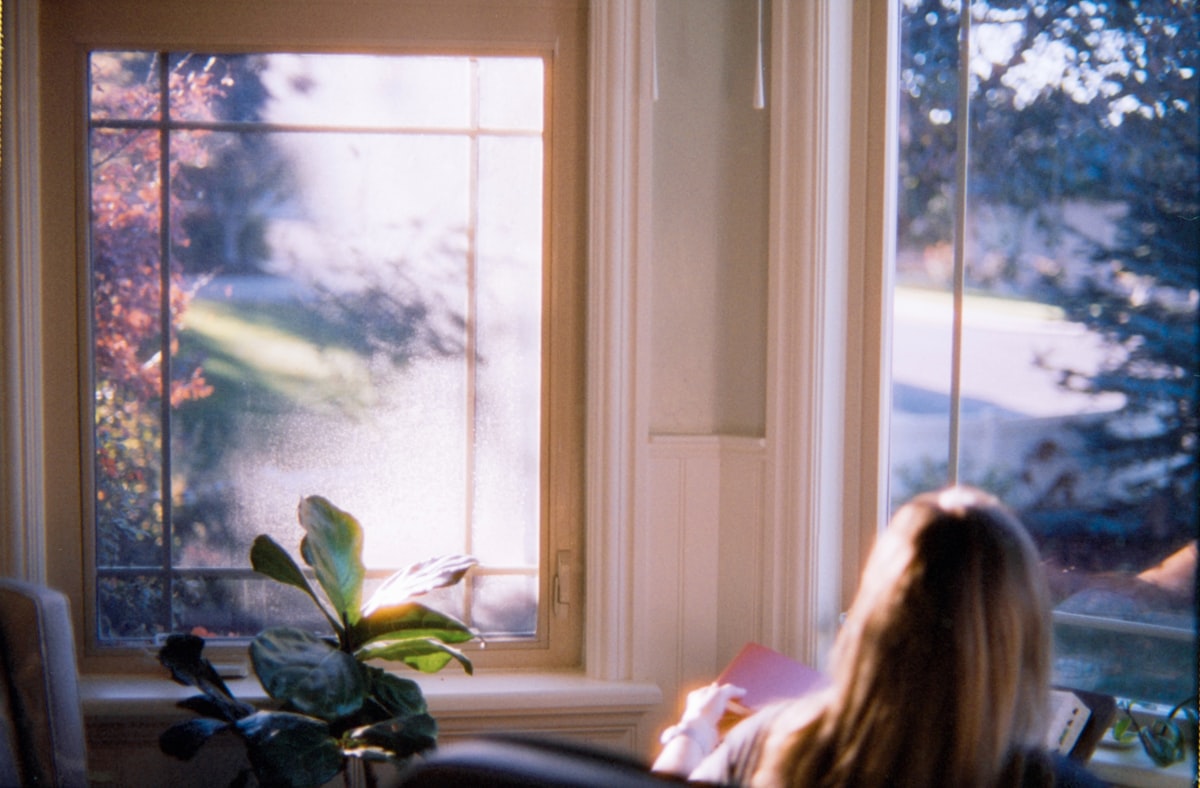 A person sitting thoughtfully by a sunlit window at home, considering whether in-home medical detox is the right next step